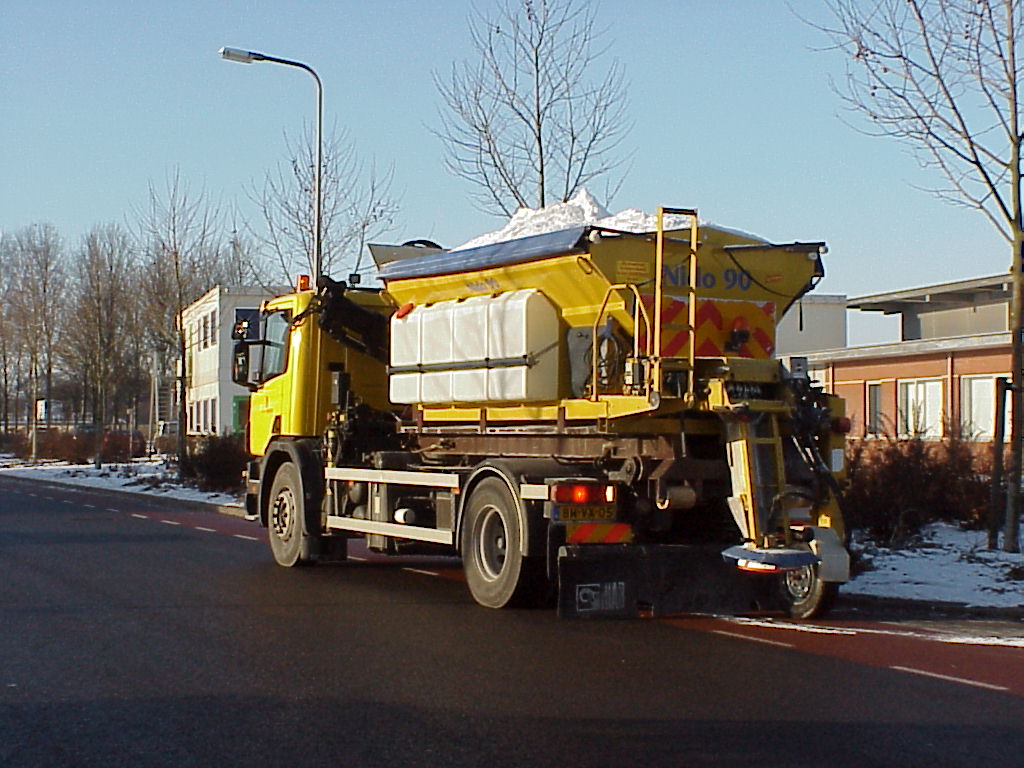 Gele strooiauto strooit zout op weg in meppel