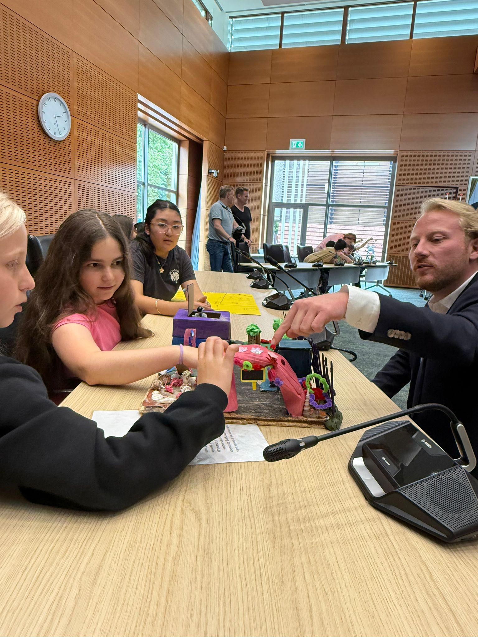 Foto van kinderen die hun ontwerp laten zien aan Wethouder van Ulzen voor de scheepfswerf in Noordpoort.
